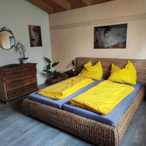 a bedroom with a bed with yellow sheets and a dresser at Haus Pluto in Deggenhausertal