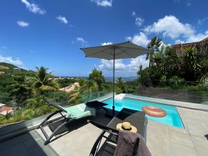 a pair of chairs and an umbrella next to a swimming pool at Villa APOLLINAIRE in Les Trois-Îlets