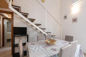 a dining room with a table with a television and stairs at Seacastle Sicily in Castellammare del Golfo
