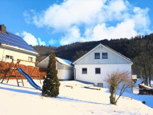 a snowy yard with a house and a playground at Haus Wanderglück in Schmallenberg