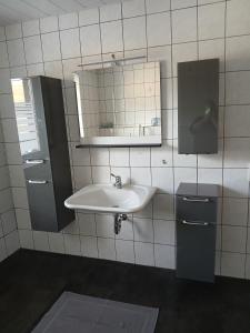 a white bathroom with a sink and a mirror at Ferienhaus Nosbers in Kleinlangenfeld