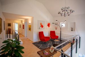 a living room with two red chairs and a chandelier at Ferienhaus Wennetraum mit Sauna in Eslohe