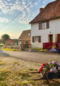 a house with a bench and flowers in front of it at Gite Charmant Forme et Bien-etre in Masseret