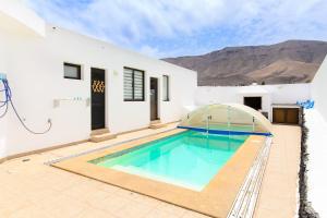 a swimming pool in the backyard of a white house at Famara Beach Apt in Famara