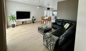 a living room with a black leather couch and a table at Raudondvaris holiday home in Raudondvaris