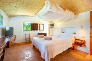 a bedroom with a white bed and a television at Sa Paret Nova in Sant Francesc Xavier