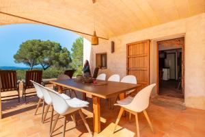 a dining room with a wooden table and white chairs at Sa Paret Nova in Sant Francesc Xavier