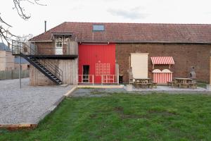 a barn with a red door and two benches at La Pause Picarde - Baie De Somme 1 in Franleu