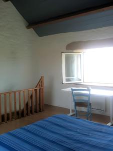 a bedroom with a bed and a blue chair at L'ancien Gonio de l'Île in Lampaul