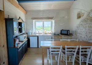 a kitchen with a wooden table and white chairs at L'ancien Gonio de l'Île in Lampaul