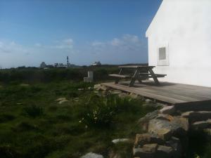 a picnic table on a deck next to a white building at L'ancien Gonio de l'Île in Lampaul