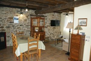 a dining room with a table and a stone wall at O Bolaño Apt 2 in Villarino de Conso