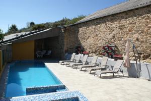 a swimming pool with chairs next to a brick building at O Bolaño Apt 2 in Villarino de Conso