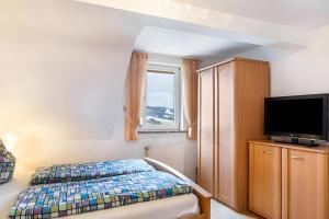 a bedroom with a bed and a flat screen tv at Zimmer Edith in Gersfeld
