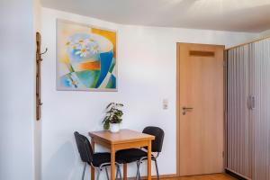 a dining room table with chairs and a painting on the wall at Zimmer Edith in Gersfeld