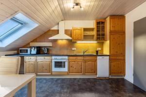 a kitchen with wooden cabinets and white appliances at Ferienwohnungen Haus Birgit in Günzgen