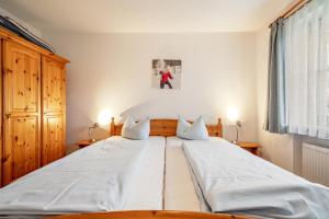 a large white bed in a bedroom with two pillows at Fewo Brünnstein - Nr 11 Pool, Sauna in Oberaudorf