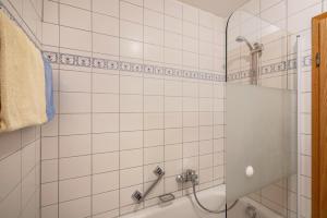 a white tiled bathroom with a shower and a tub at Fewo Brünnstein - Nr 11 Pool, Sauna in Oberaudorf +11 photos