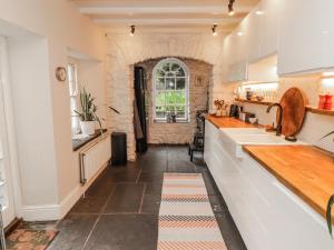 a kitchen with white cabinets and a stone wall at The Secret Garden in Narberth