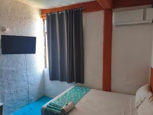 a small bed in a room with a window at Hotel Casa Lucina in Zihuatanejo
