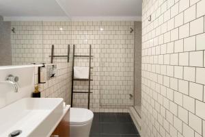 a white tiled bathroom with a toilet and a sink at Orange Apartments B in Porto +12 photos