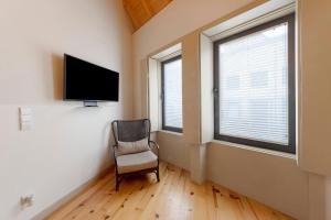a room with a chair and a flat screen tv at Orange Apartments B in Porto