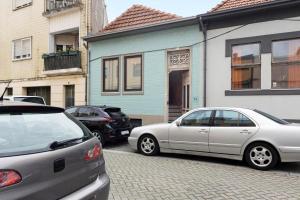 two cars parked in front of a blue house at Orange Apartments B in Porto