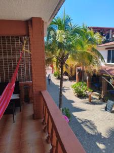 a hammock on the side of a building with palm trees at Hotel Casa Lucina in Zihuatanejo