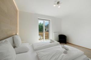 a white bedroom with two beds and a window at Premium App Hofer Elisabeth in Villabassa