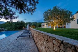 a row of benches next to a stone wall next to a pool at Sa Lluna in Sant Josep