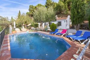 a swimming pool with blue chairs and a house at Casa Oliana in Cómpeta