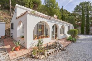 a small white house with a lot of plants at Casa Oliana in Cómpeta