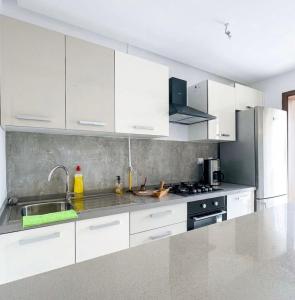 a kitchen with white cabinets and a sink and a stove at Studio Al Wahat in Douar el Hafey
