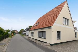 a white house with a red roof on a street at Ferienwohnung Janina in Norddeich