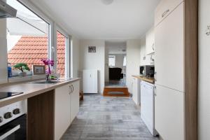 a kitchen with white cabinets and a large window at Ferienwohnung Janina in Norddeich