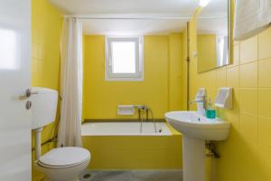 a yellow bathroom with a toilet and a sink at A Tinian Room 3 in Tinos