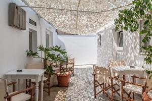 a patio with tables and chairs and a ceiling at A Tinian Room 3 in Tinos
