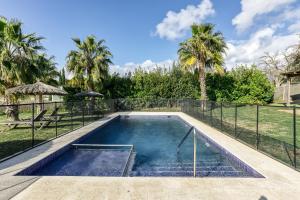 a swimming pool with a fence and palm trees at Masia Cal Ros in S'agaro