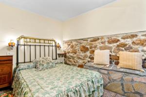 ein Schlafzimmer mit einem Bett und einer Steinwand in der Unterkunft Lorences B in Caunedo