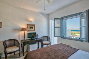 a bedroom with a bed and a desk and a window at Villa Afroditi A in Antiparos