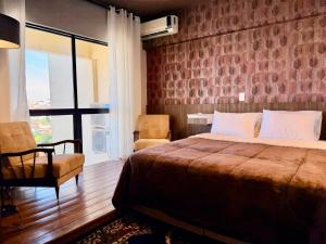 a bedroom with a bed and a chair and a window at Central Duplex Loft Near USP in São Carlos
