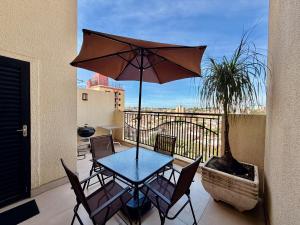 a table and chairs with an umbrella on a balcony at Central Duplex Loft Near USP in São Carlos