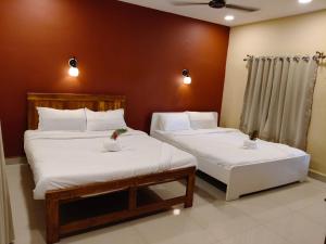 two beds in a room with white sheets at Nature yatra in Achra