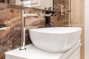 a bathroom with a white sink and a faucet at Ginex Luxury Suite, Trani in Trani
