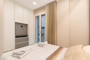 a white bedroom with a bed and a tv at Ginex Luxury Suite, Trani in Trani