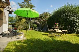 a table and chairs with a green umbrella in a yard at Ferienwohnung Sonnenblick in Putbus