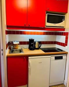 a red kitchen with a sink and a microwave at Appartement Soldanelle in La Plagne Tarentaise