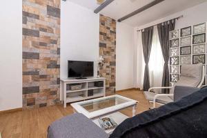 a living room with a tv and a brick wall at Casa Jimena in Vejer de la Frontera
