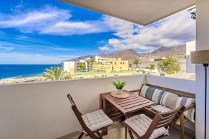 a balcony with a table and chairs and the ocean at Playa La Arena 2 Bed Apartment in Puerto de Santiago