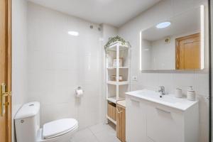 a white bathroom with a toilet and a sink at Playa La Arena 2 Bed Apartment in Puerto de Santiago